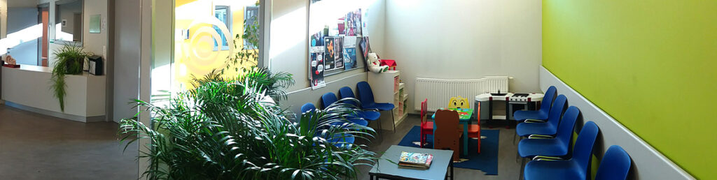Wachtkamer met stoelen en kinderspeelhoek.